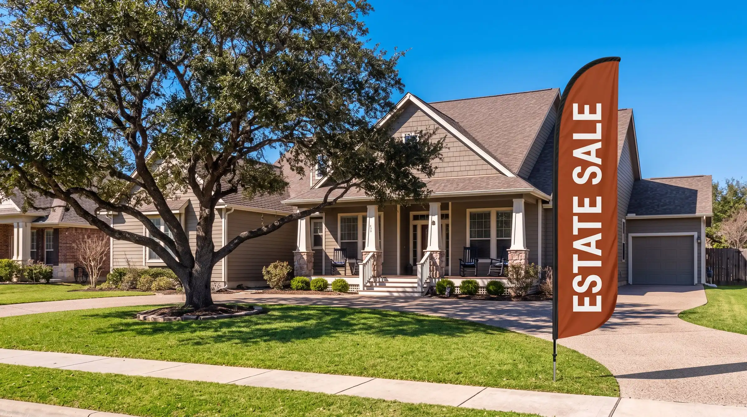 A craftsman house in Texas with a large live oak in the front yard and a red Estate Sale feather flag at the curb, on a sunny day
